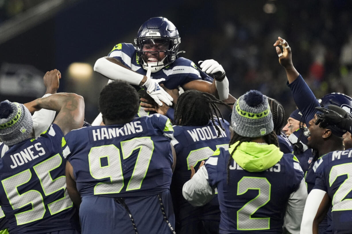 Seattle Seahawks wide receiver Dee Eskridge, top center, celebrates a touchdown on a punt return with teammates during the first half of a preseason NFL football game against the Cleveland Browns, Saturday, Aug. 24, 2024, in Seattle.