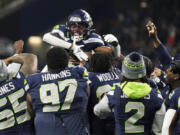 Seattle Seahawks wide receiver Dee Eskridge, top center, celebrates a touchdown on a punt return with teammates during the first half of a preseason NFL football game against the Cleveland Browns, Saturday, Aug. 24, 2024, in Seattle.