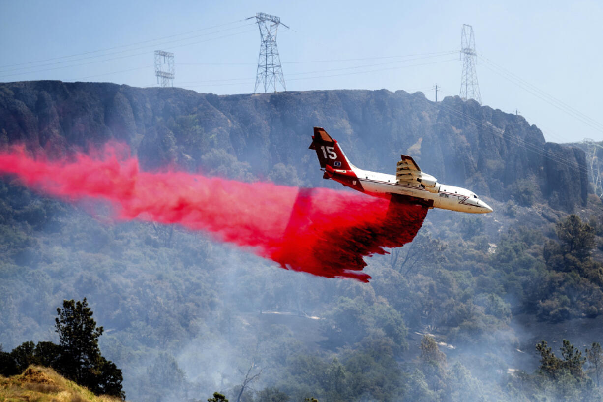 FILE - An air tanker drops retardant while trying to stop the Thompson Fire from spreading in Oroville, Calif., on Wednesday, July 3, 2024.