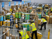 FILE - Amazon employees load packages on carts before being put on to trucks for distribution for Amazon&#039;s annual Prime Day event at an Amazon&#039;s DAX7 delivery station on July 16, 2024, in South Gate, Calif. Amazon reports earnings on Thursday, Aug. 1, 2024.