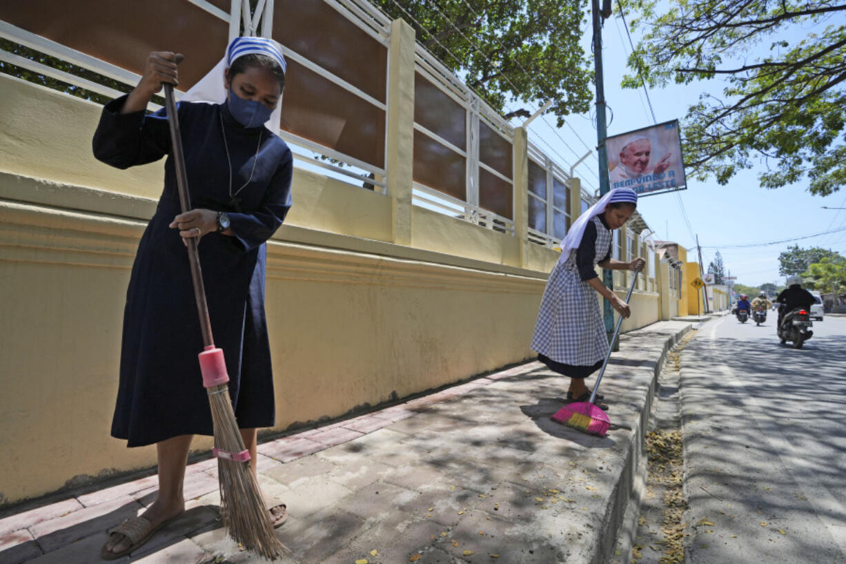 Catholic nuns sweep a sidewalk in Dili, East Timor, Monday, Aug. 12, 2024.