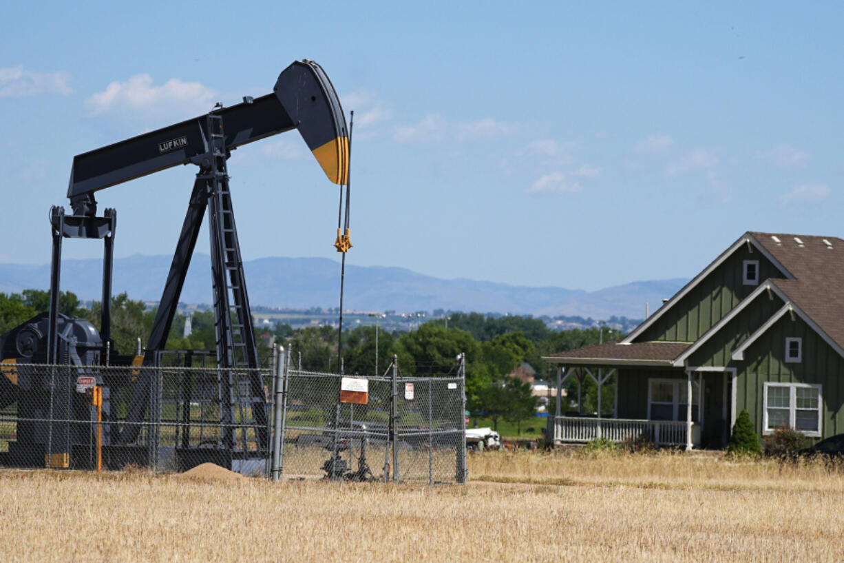 FILE - A pumpjack works on a pad near a housing development July 4, 2024, in Dacono, Colo.