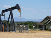 FILE - A pumpjack works on a pad near a housing development July 4, 2024, in Dacono, Colo.