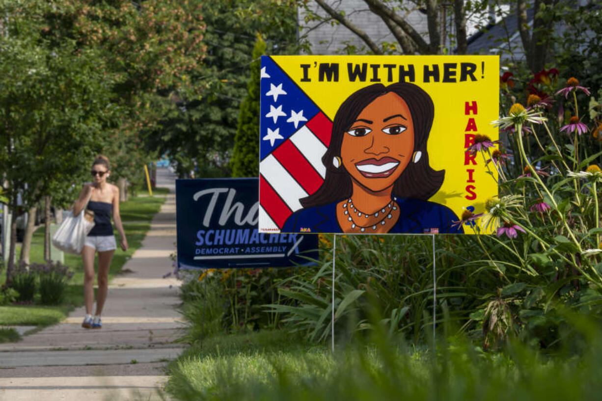 A pedestrian walks along the sidewalk past a sign in support of Kamal Harris on Tuesday, July 30, 2024, in Madison, Wis.