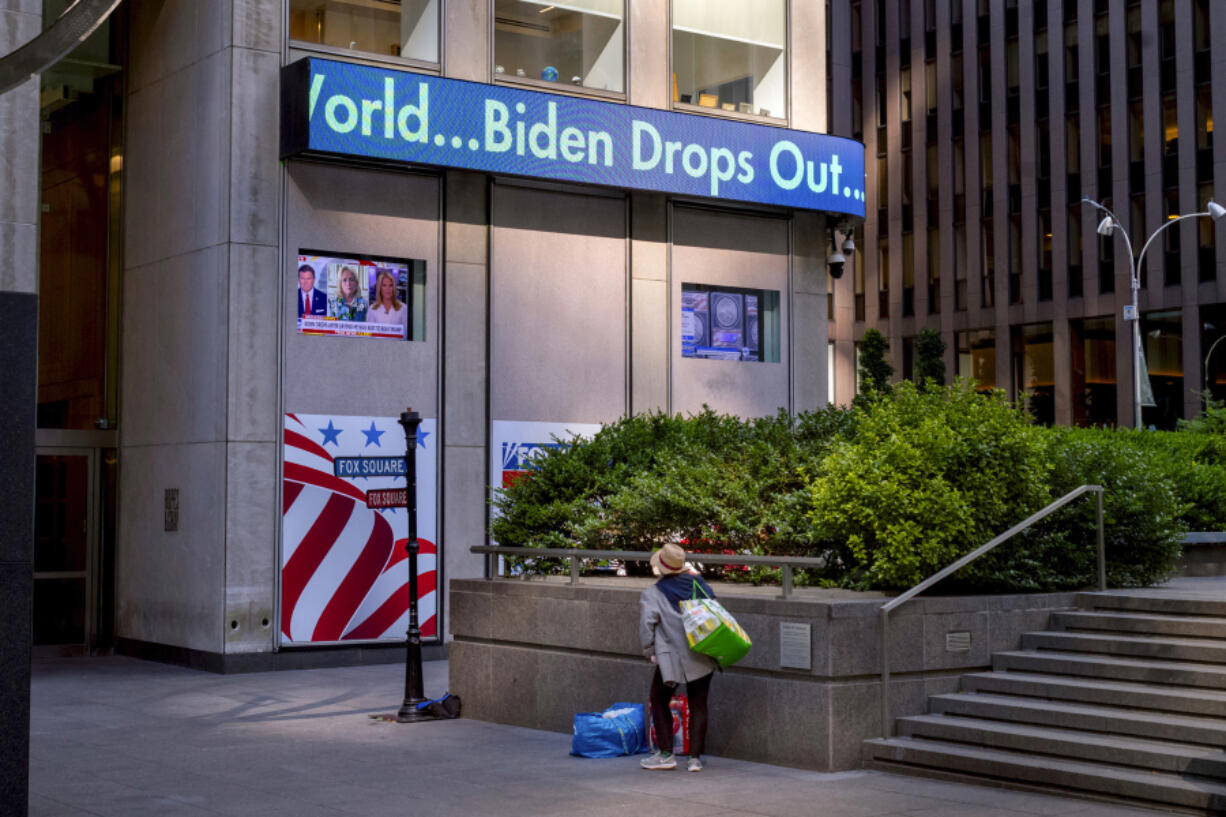 FILE - A passerby watches a news crawl appears on the side of the Fox News building in New York, Sunday, July 21, 2024, in the wake of President Joe Biden dropping out of the presidential race. Biden&rsquo;s announcement was a startling example of how fast and how far word spreads in today&rsquo;s always-connected world.