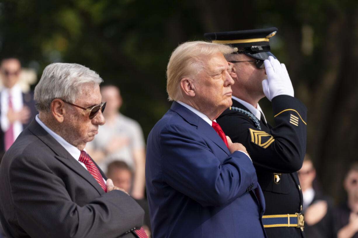 Bill Barnett, left, grandfather of Darin Taylor Hoover, and Republican presidential nominee former President Donald Trump place their hands over their heart after placing a wreath at the Tomb of the Unknown Solider in honor of Staff Sgt. Darin Taylor Hoover at Arlington National Cemetery, Monday, Aug. 26, 2024, in Arlington, Va.