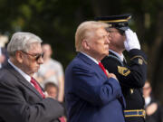 Bill Barnett, left, grandfather of Darin Taylor Hoover, and Republican presidential nominee former President Donald Trump place their hands over their heart after placing a wreath at the Tomb of the Unknown Solider in honor of Staff Sgt. Darin Taylor Hoover at Arlington National Cemetery, Monday, Aug. 26, 2024, in Arlington, Va.