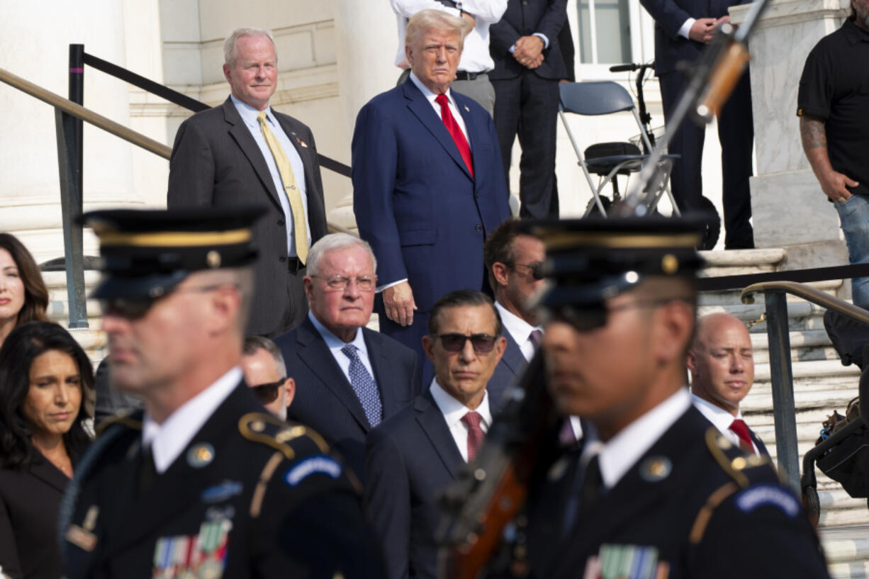 Bob Quackenbush, top left, deputy chief of staff for Arlington National Cemetery, and Republican presidential nominee former President Donald Trump watch the changing of the guard at the Tomb of the Unknown Solider at Arlington National Cemetery, Monday, Aug. 26, 2024, in Arlington, Va.