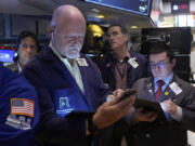 FILE - Robert Moran, left, works with fellow traders on the floor of the New York Stock Exchange, Friday, Aug. 16, 2024.