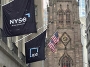 Flags fly on the side of the New York Stock Exchange with Trinity Church in the background on Wednesday, Aug. 28, 2024, in New York.