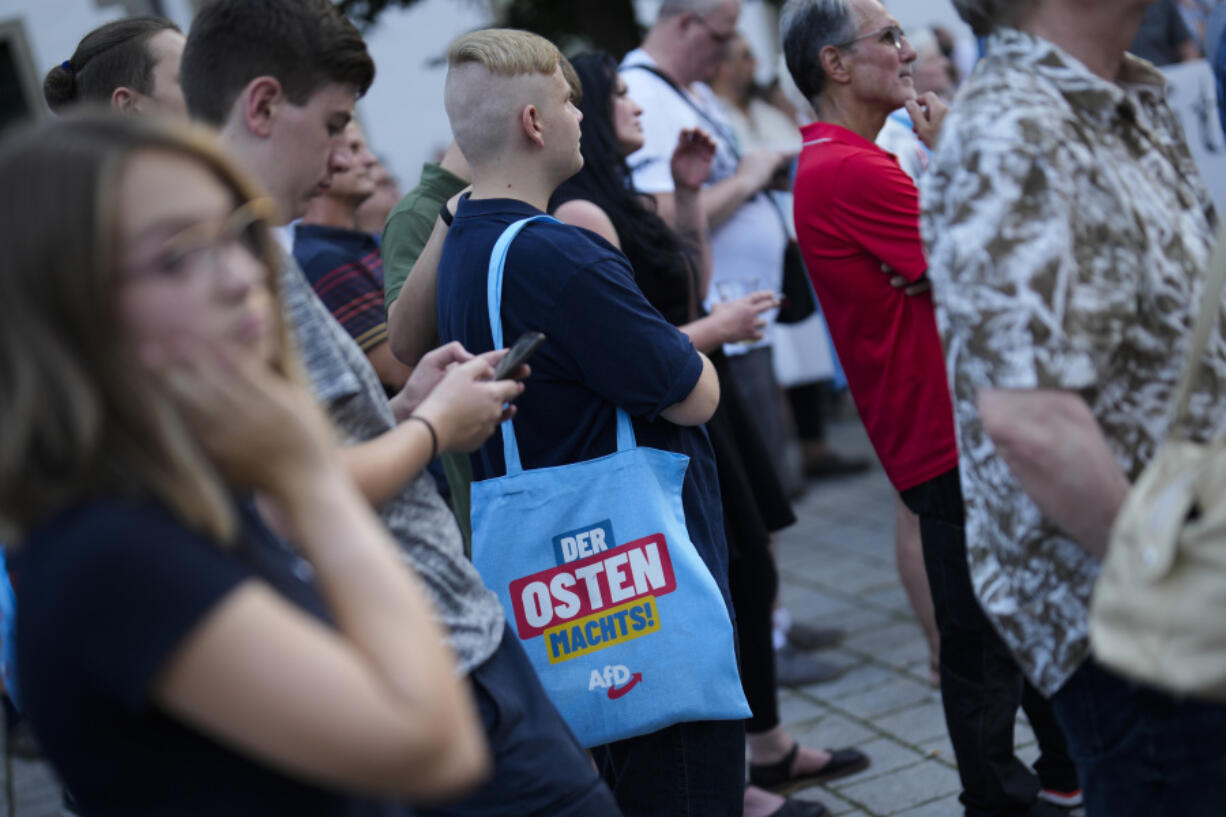 A young man with a bag reading &ldquo;The east does it&rdquo; attends an election campaign rally of the far-right Alternative for Germany, AfD, party in Suhl, Germany, Tuesday, Aug. 13, 2024.