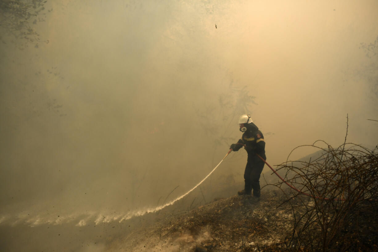 A firefighter tries to extinguish a fire in northern Athens, Monday, Aug. 12, 2024, as hundreds of firefighters tackle a major wildfire raging out of control on fringes of Greek capital.