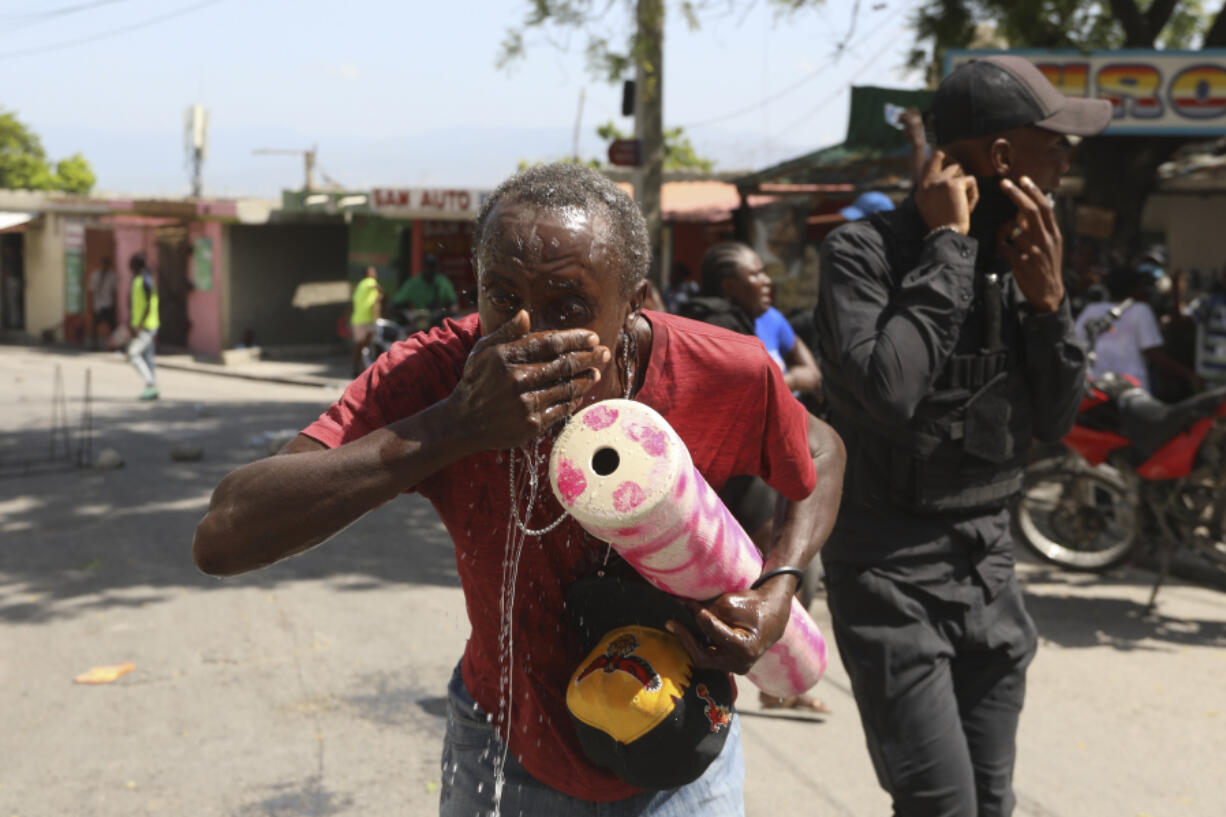 A demonstrator is affected by tear gas fired by police to disperse protesters demanding that police and the Prime Minister take immediate action against gangs in Port-au-Prince, Haiti, Monday, Aug. 19, 2024.