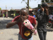 A demonstrator is affected by tear gas fired by police to disperse protesters demanding that police and the Prime Minister take immediate action against gangs in Port-au-Prince, Haiti, Monday, Aug. 19, 2024.