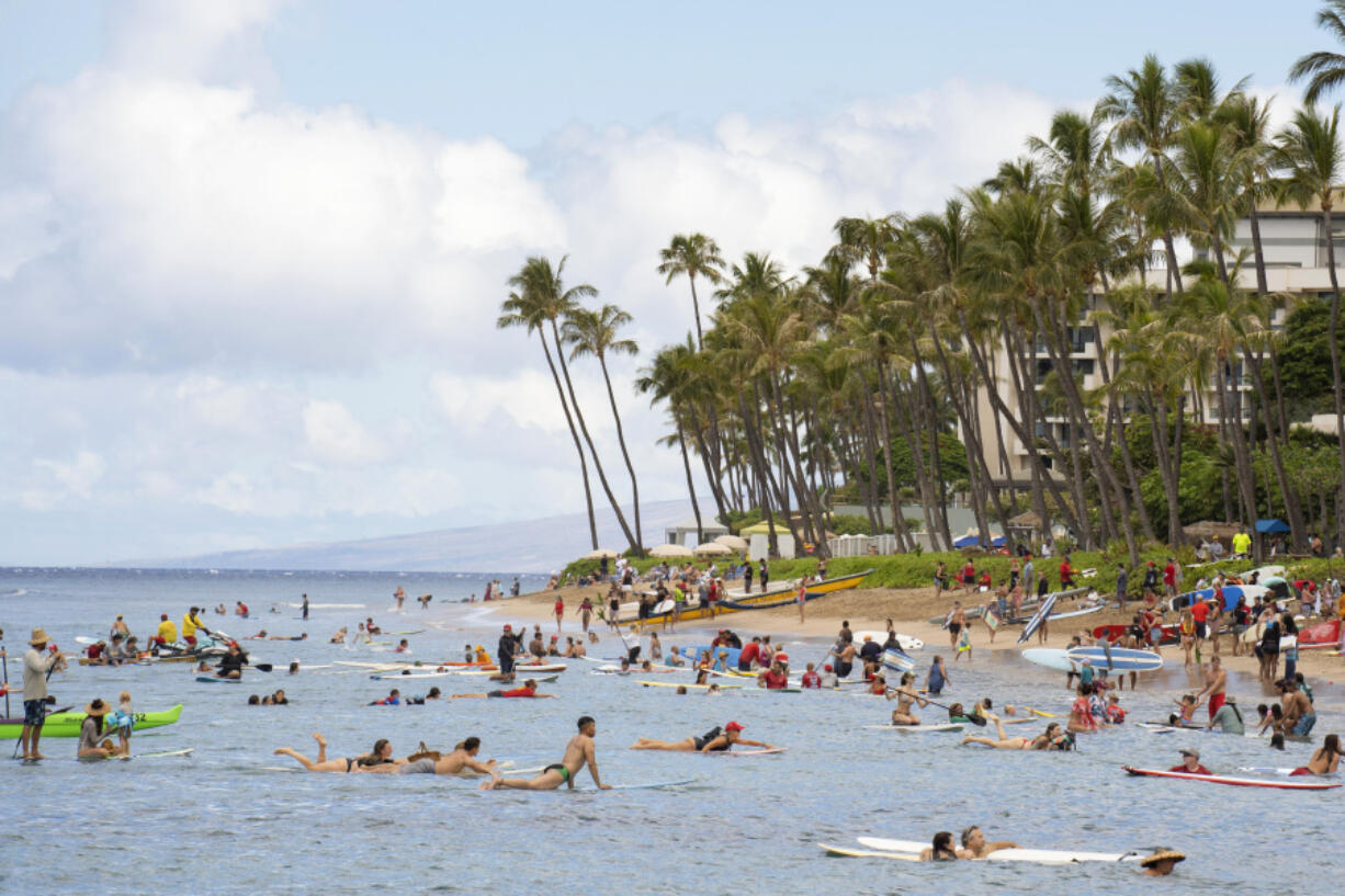 Surfers paddle back to shore at Hanakao?o Park following the paddle out ceremony held to commemorate the one-year anniversary of the Lahaina wildfire on Thursday, Aug. 8, 2024, in Lahaina, Hawaii.