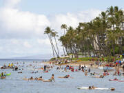 Surfers paddle back to shore at Hanakao?o Park following the paddle out ceremony held to commemorate the one-year anniversary of the Lahaina wildfire on Thursday, Aug. 8, 2024, in Lahaina, Hawaii.