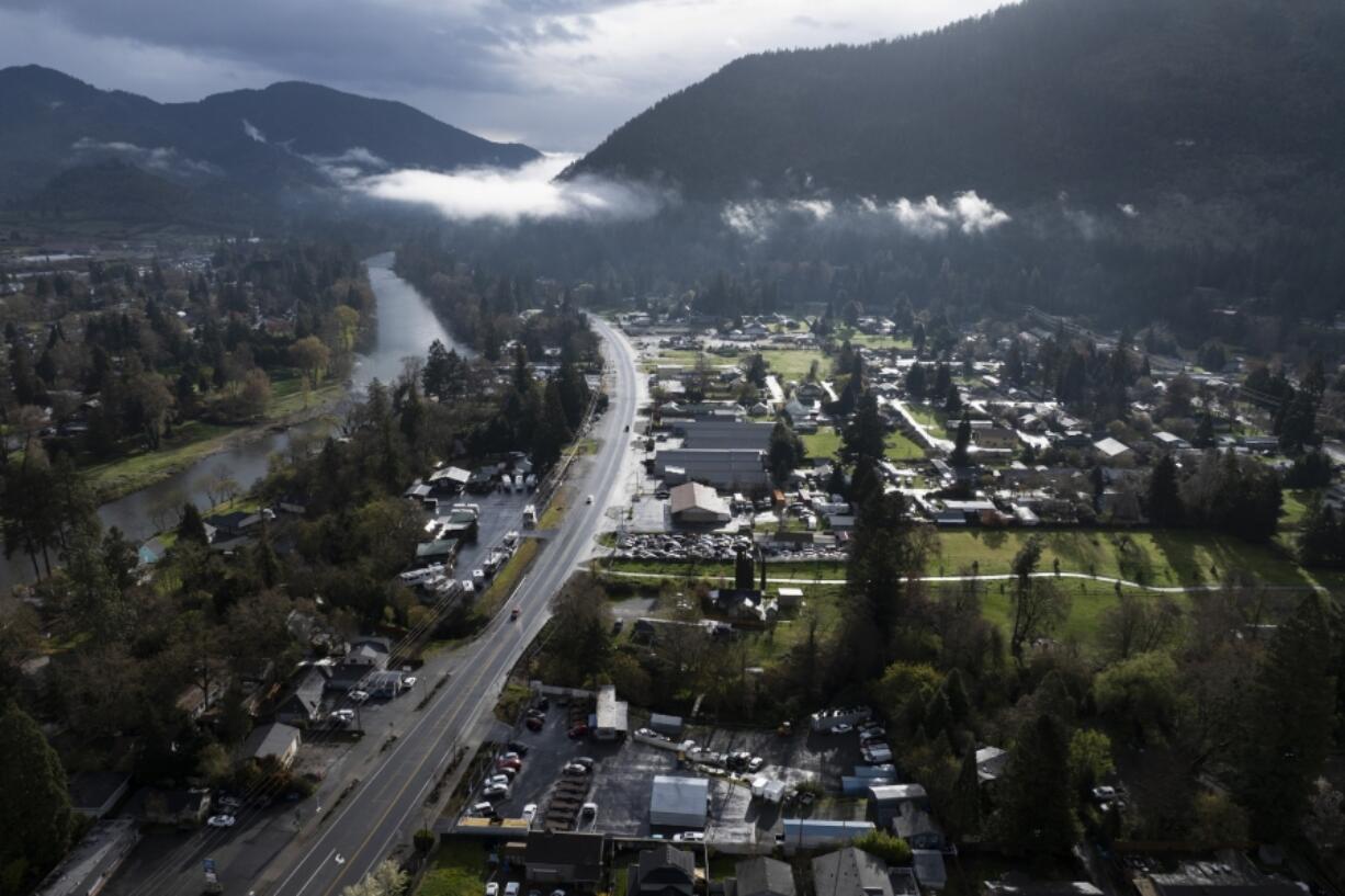 FILE - Vehicles drive down Rogue River Highway as light shines on the area on Saturday, March 23, 2024, in Grants Pass, Ore. The small Oregon city at the heart of a recent U.S. Supreme Court ruling on outdoor sleeping bans has voted to prohibit camping but establish certain areas where homeless people can go.