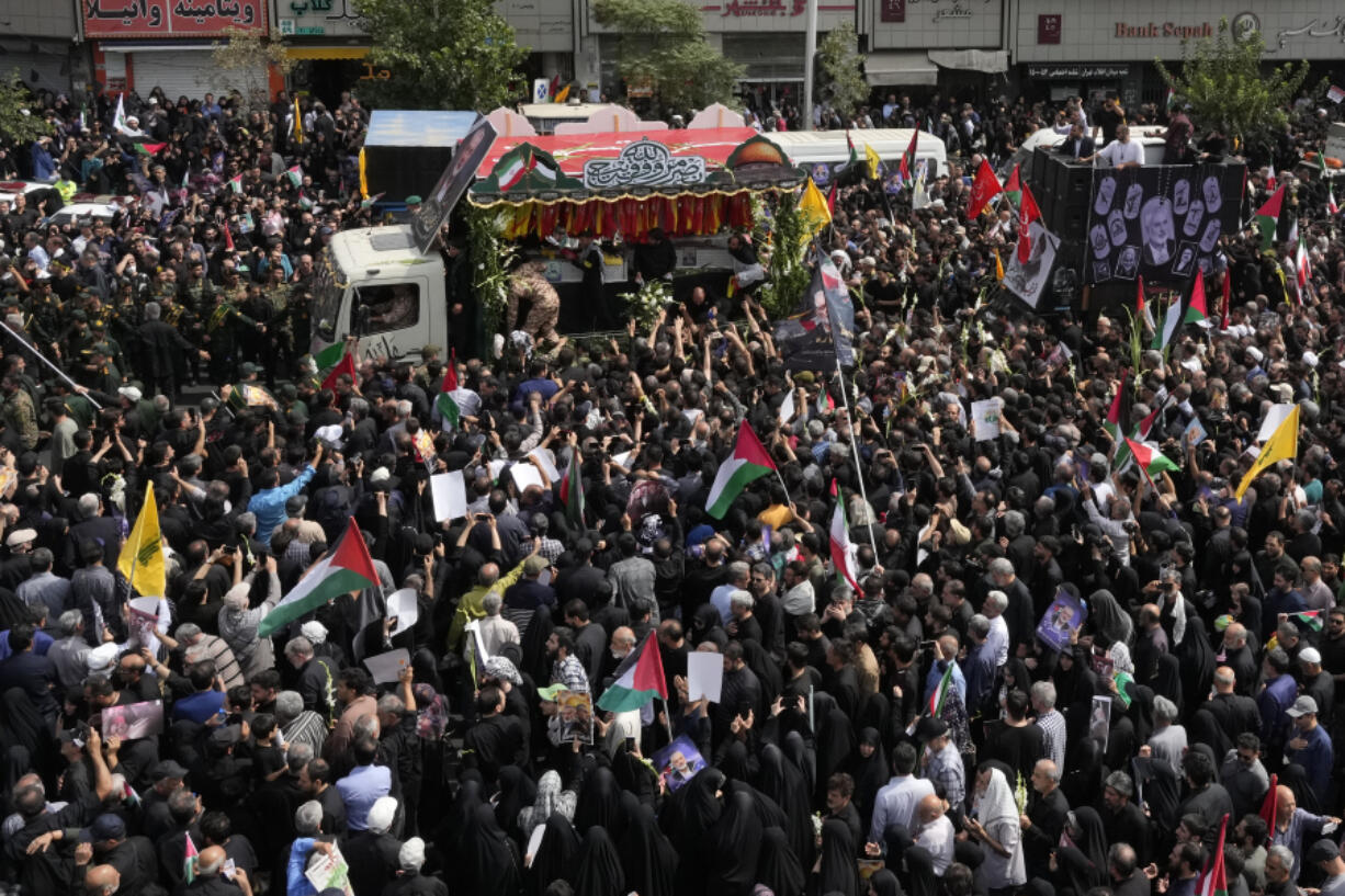 Iranians follow the truck carrying the coffins of Hamas leader Ismail Haniyeh and his bodyguard who were killed in an assassination blamed on Israel on Wednesday, during their funeral ceremony at Enqelab-e-Eslami (Islamic Revolution) Sq. in Tehran, Iran, Thursday, Aug. 1, 2024.