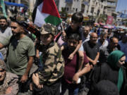 Palestinians carry children on their shoulders, one holding a toy gun and the other a Palestinian flag, as they protest the assassination of Hamas top leader Ismail Haniyeh, in the West Bank city of Ramallah, Wednesday, July 31, 2024. Two back-to-back strikes in Beirut and Tehran, both attributed to Israel and targeting high-ranking figures in Hezbollah and Hamas, have left Hezbollah and Iran in a quandary.