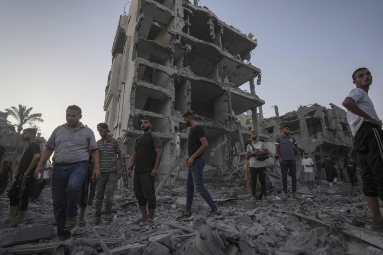 Palestinians stand in rubble after an Israeli airstrike in Deir al Balah, Gaza Strip, Tuesday, Aug. 6, 2024.