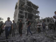 Palestinians stand in rubble after an Israeli airstrike in Deir al Balah, Gaza Strip, Tuesday, Aug. 6, 2024.