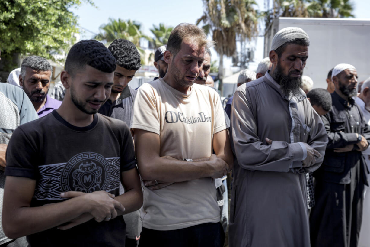 Mohammad Abu Al-Qumsan, Center, prays next to the bodies of his 4-day-old twin children, killed in the Israeli bombardment of the Gaza Strip, at a hospital in Deir al-Balah, Tuesday, Aug. 13, 2024.