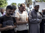 Mohammad Abu Al-Qumsan, Center, prays next to the bodies of his 4-day-old twin children, killed in the Israeli bombardment of the Gaza Strip, at a hospital in Deir al-Balah, Tuesday, Aug. 13, 2024.