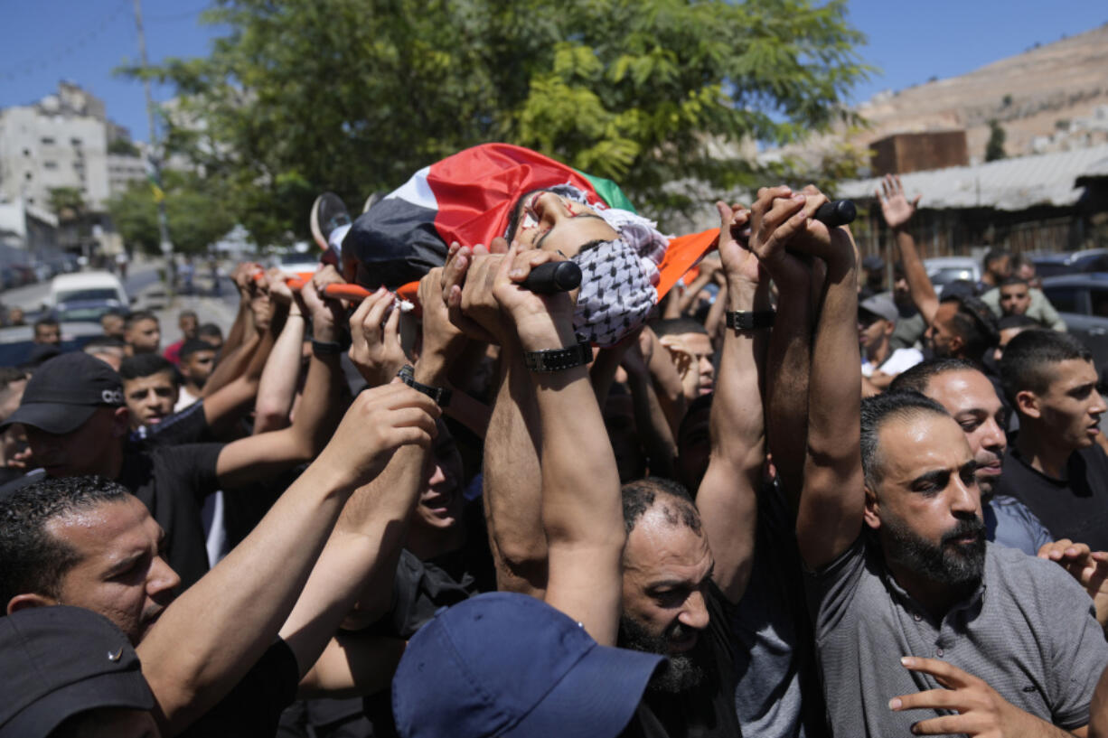 Mourners carry the bodies of Palestinians Wael Misha, 18, front and Ahmed Sheikh Khalil, 20, both killed by an airstrike overnight during an army operation in the occupied West Bank, during their funeral in the refugee Camp of Balata, in Nablus, Thursday, Aug. 15, 2024.