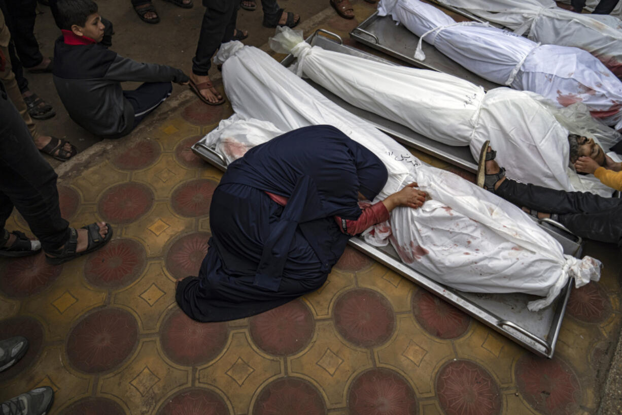 FILE - A woman mourns the covered bodies of her child and her husband killed in an Israeli army bombardment of the Gaza Strip, in the hospital in Khan Younis, Tuesday Dec. 5, 2023.