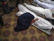 FILE - A woman mourns the covered bodies of her child and her husband killed in an Israeli army bombardment of the Gaza Strip, in the hospital in Khan Younis, Tuesday Dec. 5, 2023.