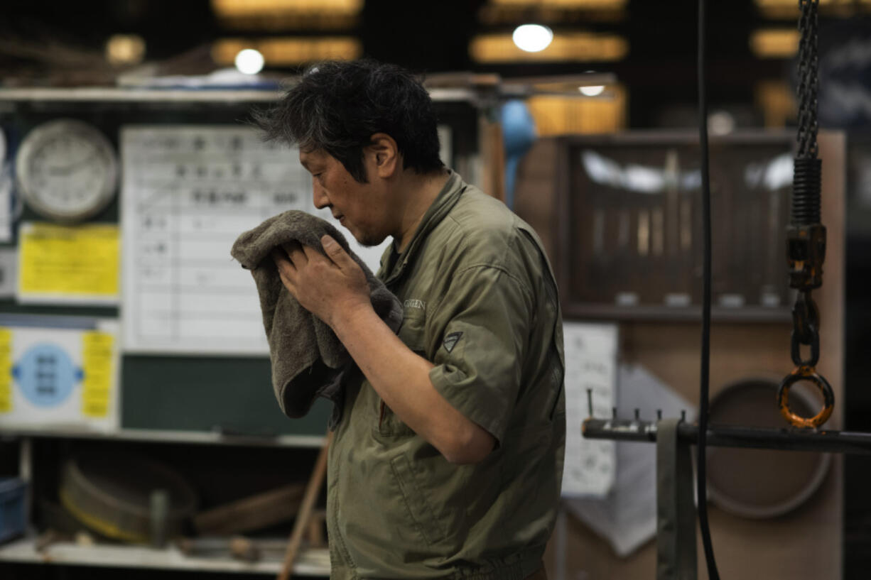 Craftsman Katsunori Suzuki takes a break May 16 while making a cast iron pot by hand at the Oigen foundry in Oshu, northeastern Japan.