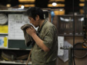 Craftsman Katsunori Suzuki takes a break May 16 while making a cast iron pot by hand at the Oigen foundry in Oshu, northeastern Japan.