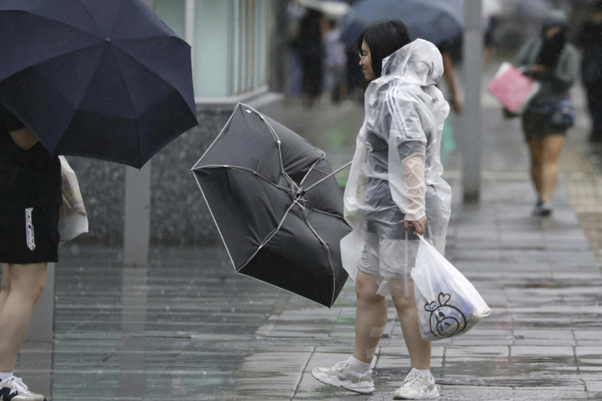 People holding umbrella, struggles with the strong wind as a typhoon is approaching in Fukuoka, western Japan, Thursday, Aug. 29, 2024.