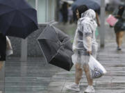 People holding umbrella, struggles with the strong wind as a typhoon is approaching in Fukuoka, western Japan, Thursday, Aug. 29, 2024.