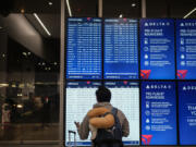 A person looks at the flight information screen in the Delta Airlines ticketing area at the Los Angeles International Airport in Los Angeles, Friday, Aug. 30, 2024. (AP Photo/Jae C.