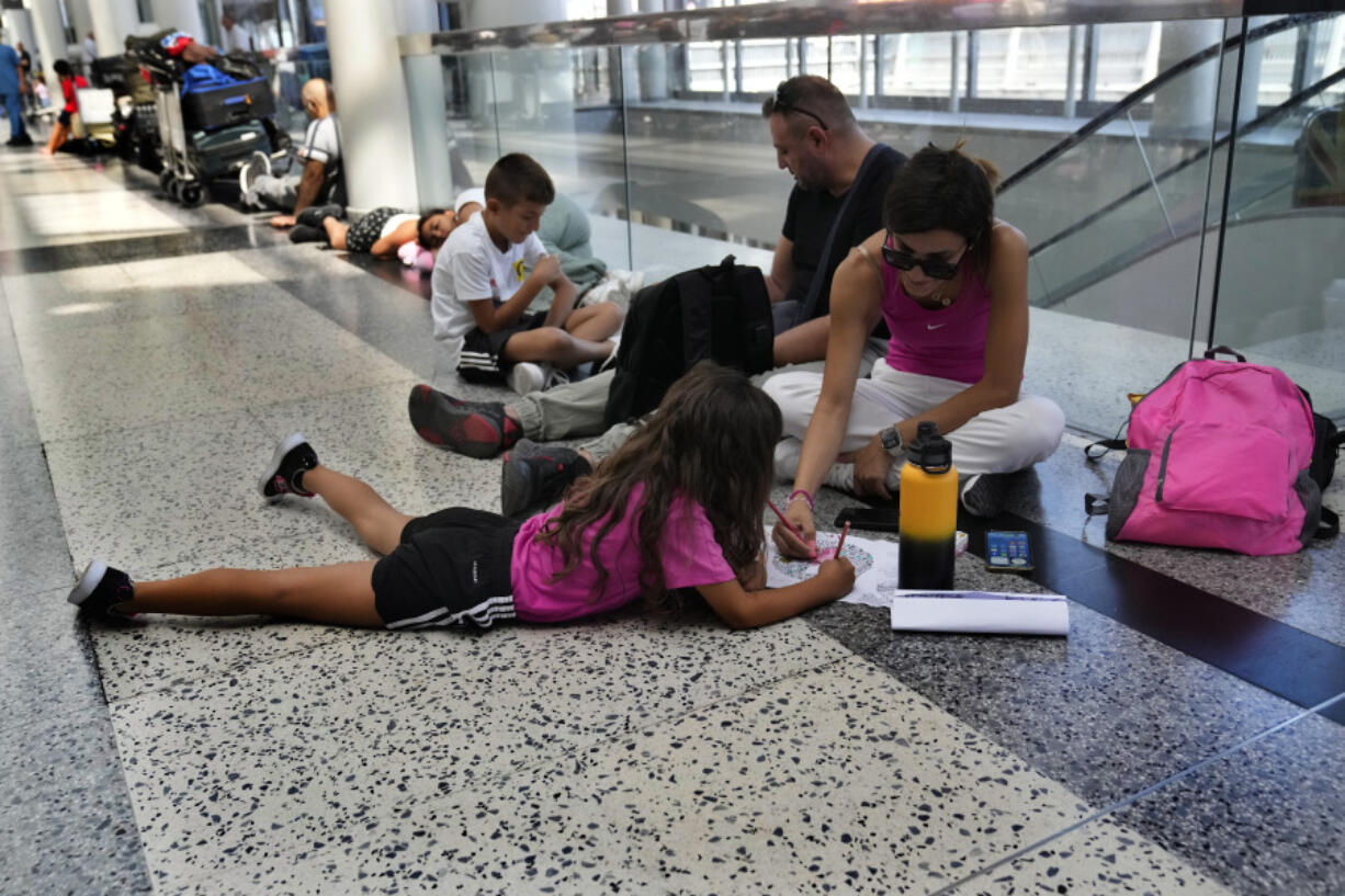 FILE - Passengers whose flights were cancelled sit at the departure terminal ground of Rafik Hariri International Airport in Beirut, Lebanon, Aug. 5, 2024.