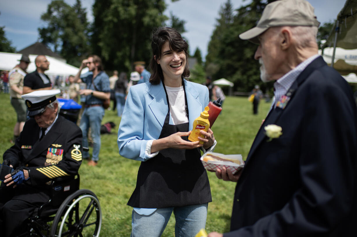 Congresswoman Marie Gluesenkamp Perez chats with participants including veteran Mike Burton, right, of the Community Military Appreciation Committee while providing condiments for their hot dogs at Fort Vancouver National Historic Site on May 27.