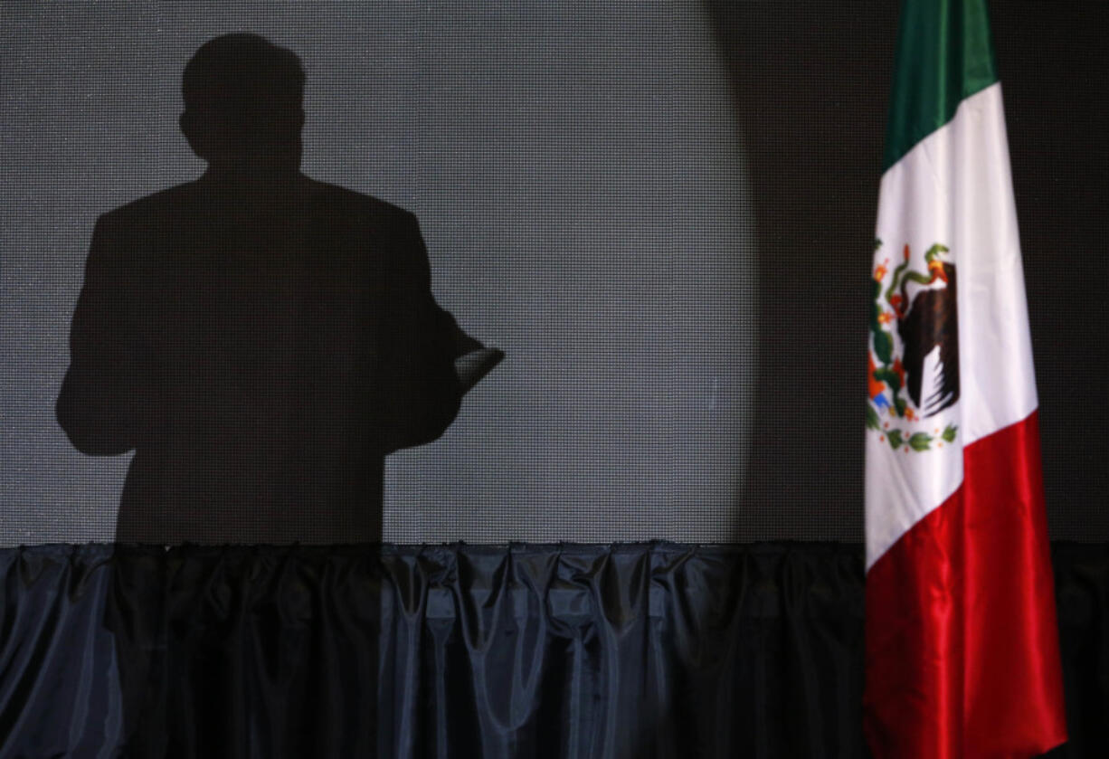 FILE - The shadow of presidential candidate Andres Manuel Lopez Obrador, founder of the ruling party, Morena, is cast on a screen as he gives his first victory speech at his campaign headquarters at the Hilton hotel in Mexico City, late July 1, 2018.