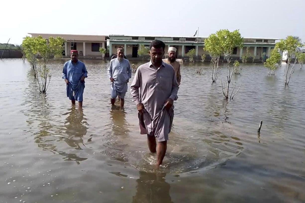 Villagers wade through flood area caused by heavy monsoon rains near Sohbat Pur, an area of Pakistan&rsquo;s southwestern Baluchistan province, on Monday.