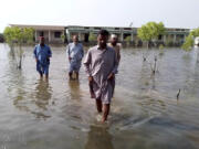 Villagers wade through flood area caused by heavy monsoon rains near Sohbat Pur, an area of Pakistan&rsquo;s southwestern Baluchistan province, on Monday.