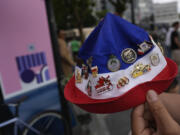 Neighborhood resident Lahlouh Wahab shows off all the 2024 Olympic pins he has been able to collect by interacting with athletes and staff from various teams outside the entrance to the Olympic Village, at the 2024 Summer Olympics on July 23 in Paris.