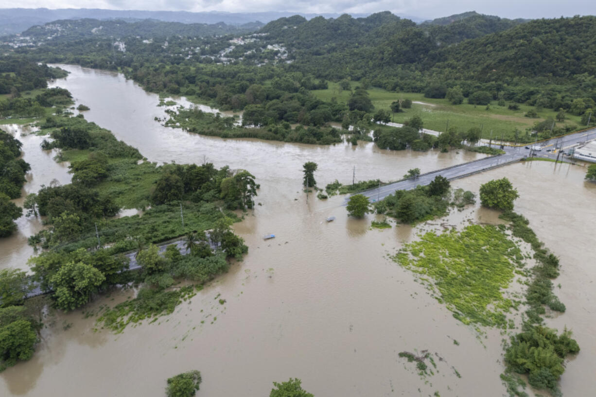 La Plata river floods a road after Tropical Storm Ernesto passed through Toa Baja, Puerto Rico, Wednesday, Aug. 14, 2024.