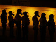 FILE - Police wait to advance after tear gas was used to disperse a crowd during protests against the shooting death of Michael Brown Jr. on Aug. 17, 2014 in Ferguson, Mo.