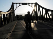 FILE - A cyclist passes over the Glienicke Bridge between Potsdam and Berlin, Germany, on May 6, 2009. They sometimes see those who are part of the swap as they pass each other on an airport tarmac or, as in the Cold War, the Glienicke Bridge connecting West Berlin to Potsdam. In decades of prisoner exchanges, those released have included spies, journalists, drug and arms dealers, and even a well-known athlete.