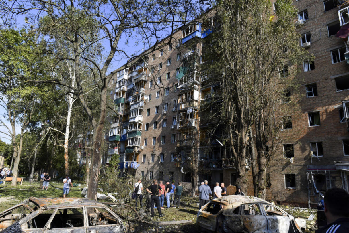 People gather at an apartment building damaged after shelling by the Ukrainian side in Kursk, Russia, Sunday, Aug. 11, 2024.