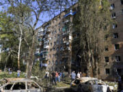 People gather at an apartment building damaged after shelling by the Ukrainian side in Kursk, Russia, Sunday, Aug. 11, 2024.