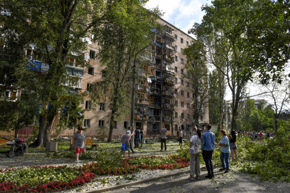 People gather at an apartment building damaged after shelling by the Ukrainian side in Kursk, Russia, Sunday, Aug. 11, 2024.