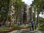 People gather at an apartment building damaged after shelling by the Ukrainian side in Kursk, Russia, Sunday, Aug. 11, 2024.