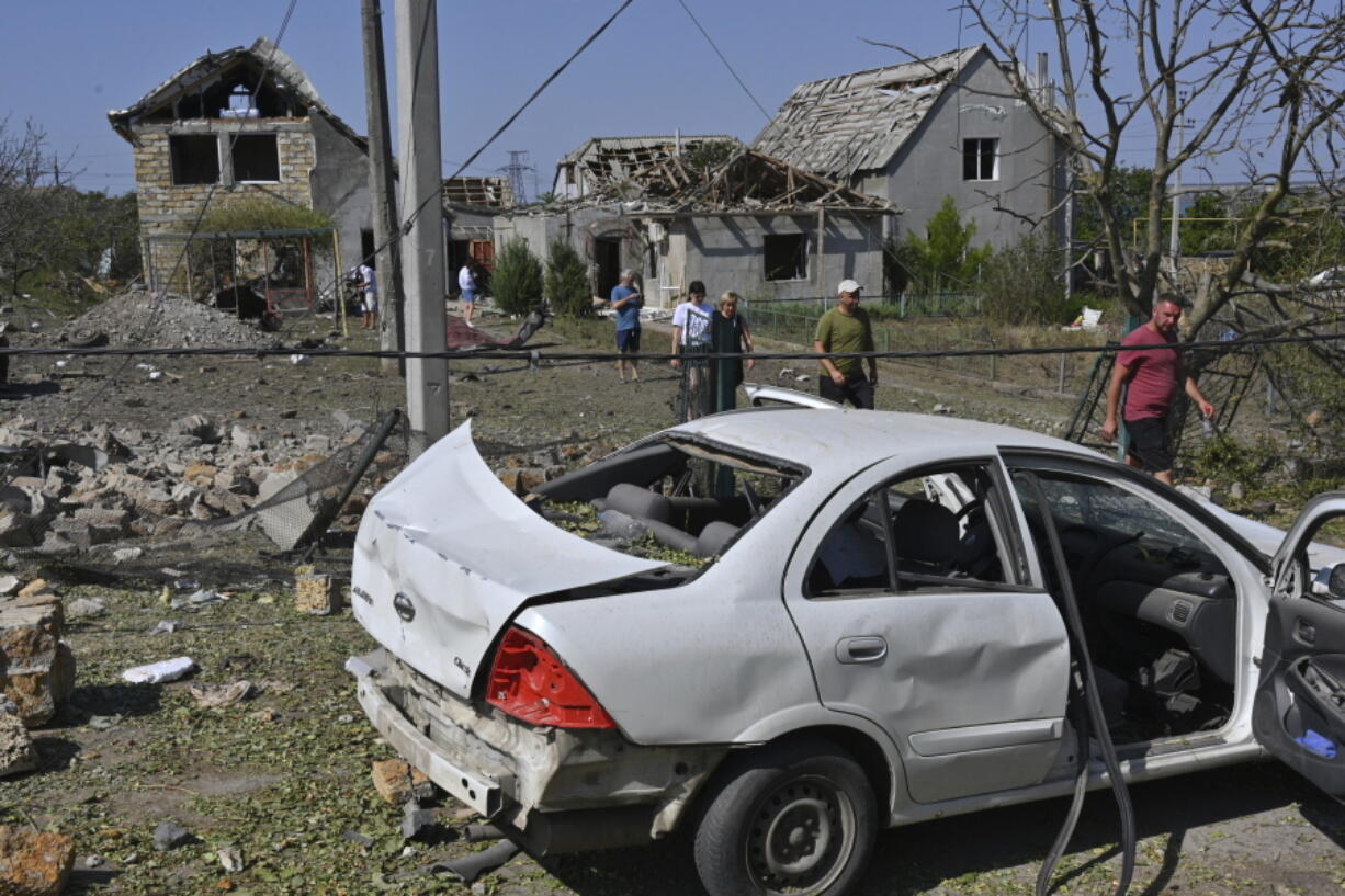 People walk in front of their damaged houses after Russian rocket attack in Usatove village near Odesa, Ukraine, Monday, Aug. 26, 2024.