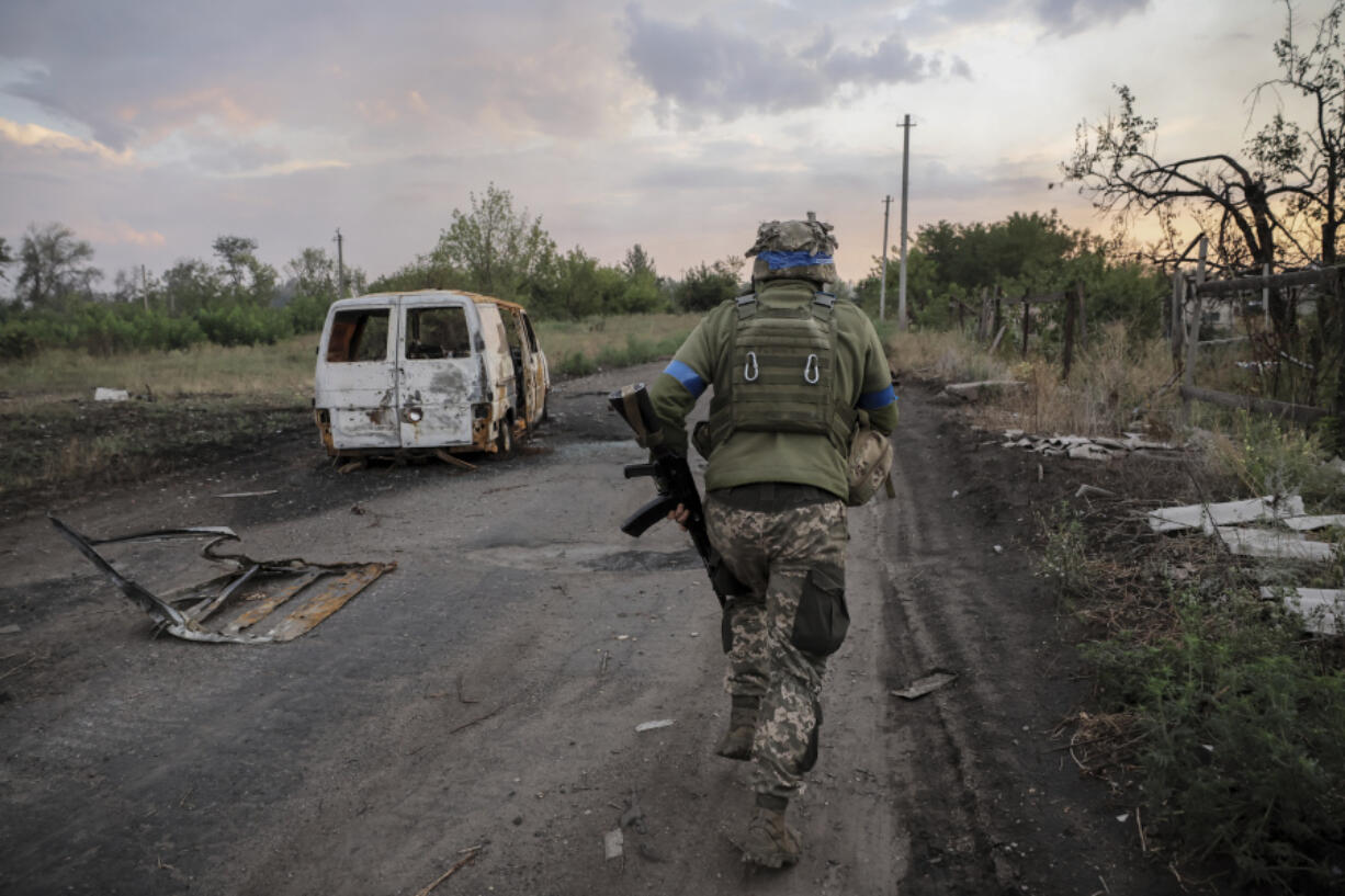 In this photo provided by Ukraine&#039;s 24th Mechanised Brigade press service, a serviceman of the 24th Mechanised Brigade runs past a damaged car at the frontline town of Chasiv Yar, Donetsk region, Ukraine, Tuesday, Aug. 6, 2024.